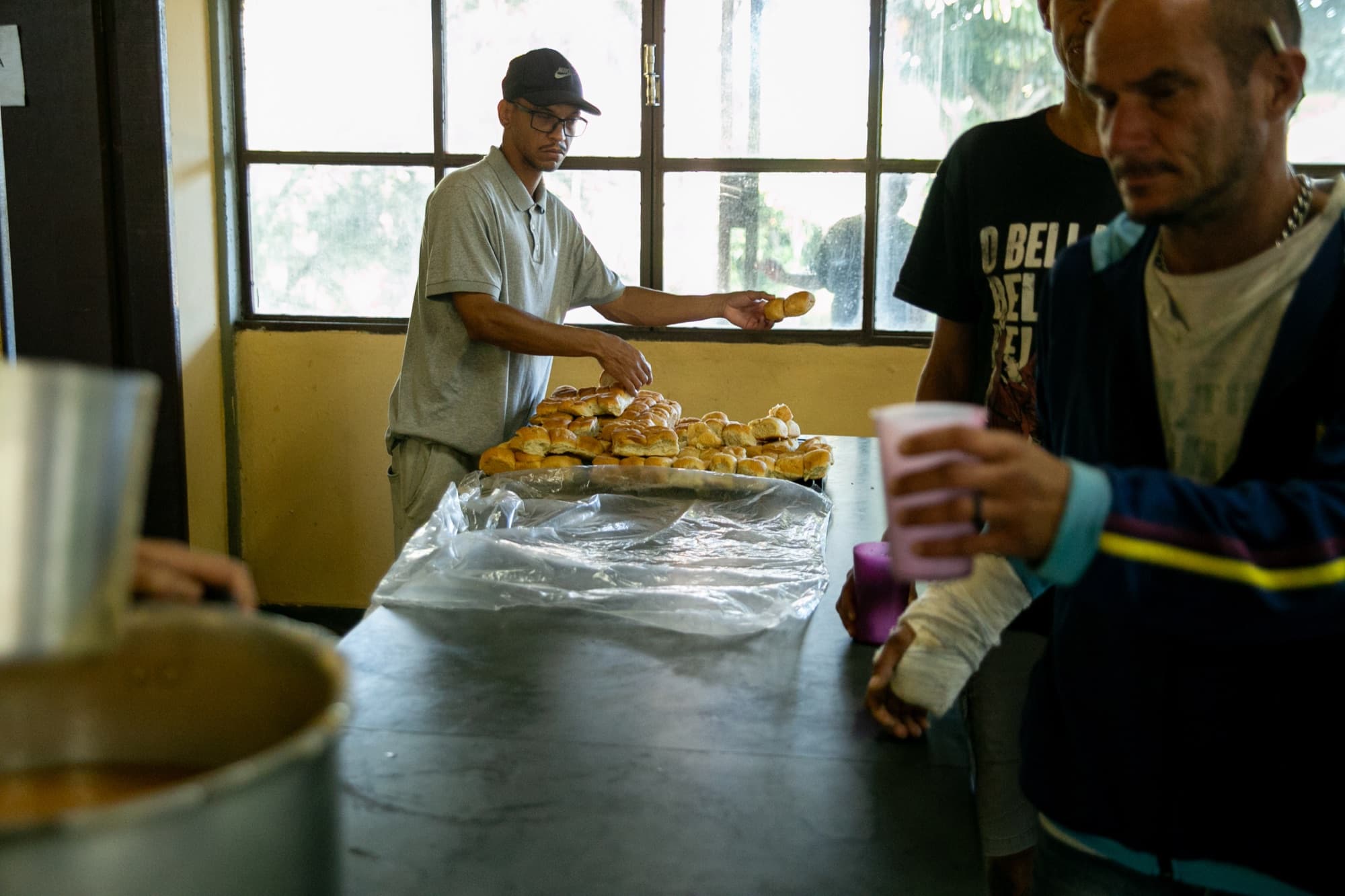Acolhido servindo pão na cozinha da unidade